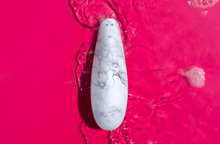 ピンクの水面に浮かぶ大理石模様の製品。水滴が周りに広がり、製品のデザインと清潔感が強調されている