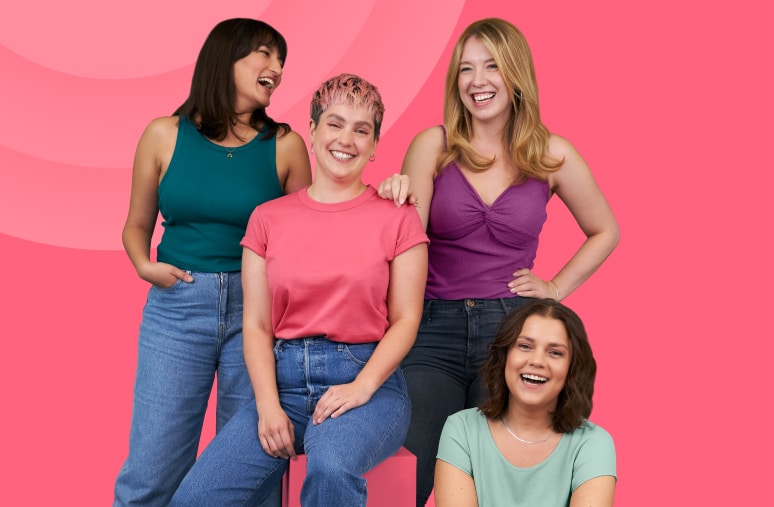 ピンクの背景の前で笑顔を見せる4人の女性、楽しさと親しみやすさを表現しています