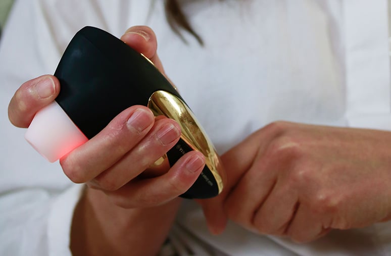 黒と金の吸引タイプのおもちゃが手に持たれており、赤く光るライトが点灯しています